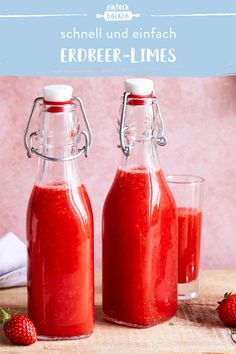 two glass bottles filled with red liquid next to strawberries