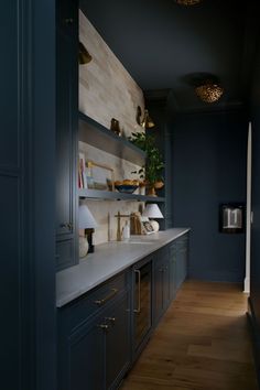 a kitchen with dark blue cabinets and white counter tops, along with wooden flooring