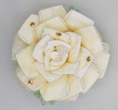 a white flower with bees on it sitting in the middle of a gray surface and surrounded by green leaves