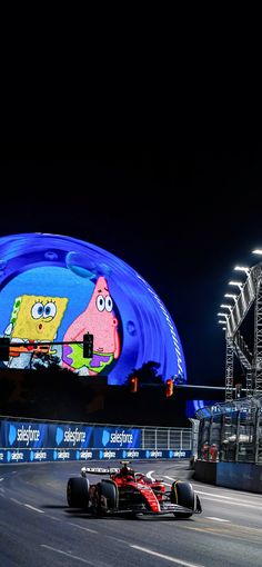 two racing cars driving down a race track at night