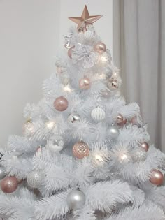 a white christmas tree with pink and silver ornaments