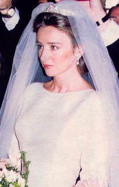 a woman in a wedding dress and veil walking down the aisle with her father, who is wearing a tuxedo