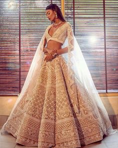 a woman in a gold and white bridal gown, with her hands on her hips