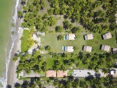 an aerial view of a beach with palm trees and houses in the foreground, looking down at the ocean