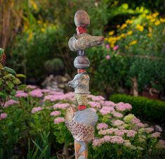 three stacked rocks in the shape of birds on top of each other near some flowers