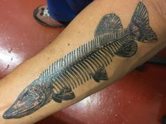 a fish skeleton tattoo on the arm of a person's left leg, which is black and grey