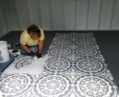 a woman is painting the floor with white paint and black stencils on it