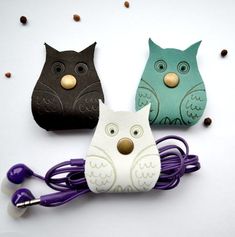 three owls with ear buds are sitting next to each other on a white surface, surrounded by coffee beans