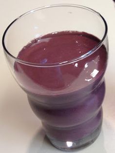 a glass filled with purple liquid sitting on top of a table