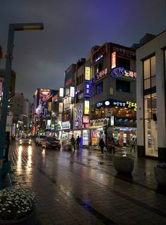 a city street at night with people walking on the sidewalk