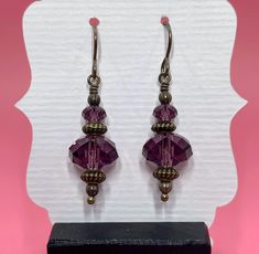 These delicate earrings are made with amethyst Swarovski crystals, antique brass spacer beads and small round antique brass beads. The earrings measure approximately 1 3/4 inches from the top of the antique brass earwire.  Click here to see other earrings in my shop: https://www.etsy.com/shop/JewelryDesignsByRita?section_id=14765680 I have been designing and making jewelry since 2010. I use only the highest quality materials such as Swarovski crystals, Swarovski pearls, gemstones, sterling silver, Gold Vermeil, gold filled components and artisan made lampwork beads. If you have any questions as you browse, please feel free to ask. Self-Representing Artist in Jewelry Design, Member #3879 Elegant Purple Crystal Earrings With Dangling Beads, Purple Crystal Earrings With Round Beads For Gift, Purple Crystal Dangle Earrings With Beads, Purple Gemstone Bead Dangle Earrings, Purple Faceted Bead Dangle Crystal Earrings, Swarovski Crystal Earrings, Delicate Earrings, Swarovski Pearls, Lampwork Beads