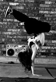 a woman is doing a handstand on the ground in front of a brick wall