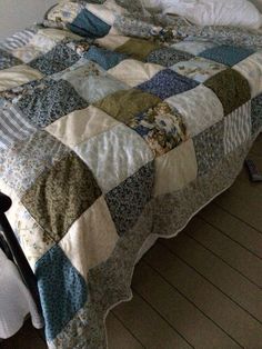 an unmade bed with a quilt on it in a room next to a window