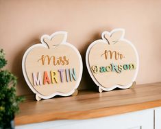 two wooden apple shaped magnets with the words miss and mr written in multicolored letters