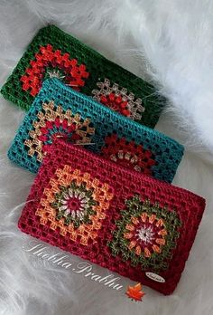 three crocheted purses sitting on top of white fur