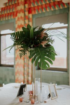 there is a tall plant in the center of this table with candles and pictures on it