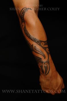 a man with a tattoo on his arm and leg is standing in front of a black background