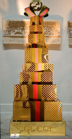 a very tall christmas tree made out of gold and red boxes with ribbons on it