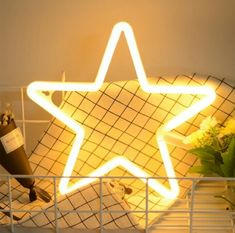 a star shaped neon sign sitting on top of a shelf next to a vase with flowers