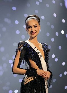 a woman in a black and white dress standing on a stage with lights behind her