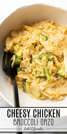 a white bowl filled with pasta and broccoli on top of a table next to a black fork