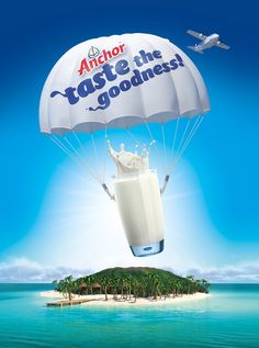 an advertisement for anchor taste the goodness milk is being lifted by a parachute over a small island