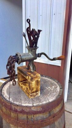 an old fashioned metal device on top of a wooden barrel with chains attached to it