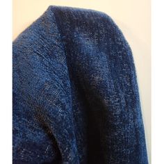 a blue sweater hanging up against a white wall with the bottom part of it folded down