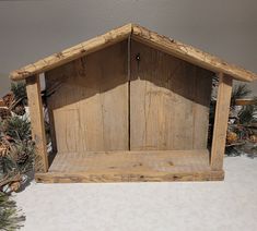 a small wooden hut sitting on top of a table next to pine cones and branches