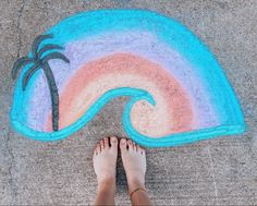 someone is standing in front of a chalk drawing with a palm tree and rainbow colors