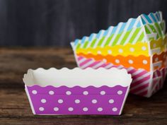 three colorful cupcake cases sitting on top of a wooden table