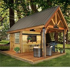 a small wooden shed sitting on top of a lush green field in front of trees