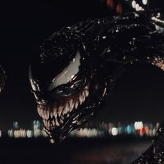 a close up of a spider man face in front of a cityscape at night