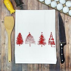 a kitchen towel with red christmas trees on it next to eggs and a spatula