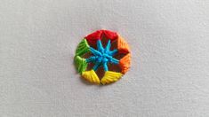 an embroidered brooch with multicolored flowers on white linen background, closeup