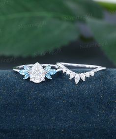 an engagement ring with blue topaz and white diamonds on the side, sitting on a piece of fabric