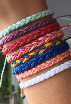 several different colored braided bracelets on someone's arm