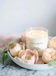 a candle sitting on top of a white plate filled with flowers