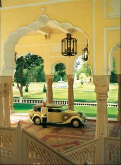 an old car is parked in the middle of a room with columns and arches on either side