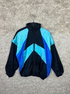 Vintage shell jacket with detachable sleeves. To close with stand-up collar and zip. One pocket on the left and one on the right. Colours: black, turquoise, blue Material : 100% Nylon, Lining: 100% Cotton Size M Please note dimensions!! Length: 70cm Width: 62cm Arm length from collar: 79 cm If you have any questions or need more information, just write to me :) Retro Blue Nylon Outerwear, Retro Blue Nylon Windbreaker, Vintage Blue Nylon Track Jacket, Retro Blue Hooded Track Jacket, Blue Retro Windbreaker For Outdoor Activities, 90s Style Blue Nylon Track Jacket, 90s Style Blue Track Jacket For Outdoor, Retro Black Windbreaker For Outdoors, Retro Black Windbreaker For Outdoor