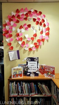 a book shelf with books and paper hearts on it