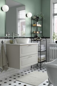 a bathroom with green walls and black and white tile flooring on the wall, along with a large mirror over the sink