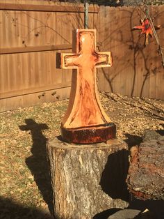 a wooden cross sitting on top of a tree stump next to a fenced in area