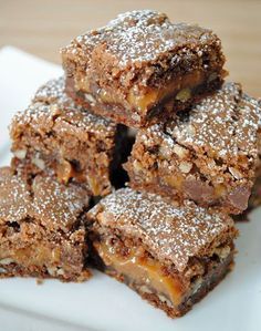 a white plate topped with brownies covered in powdered sugar