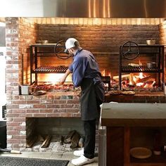 a man standing in front of a brick oven