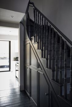 a black and white photo of a stair case in a house with dark wood flooring