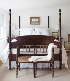 a bedroom with a four poster bed and white linens on the pillows, along with two chairs