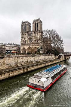 a large boat traveling down a river next to a tall building with a cathedral in the background