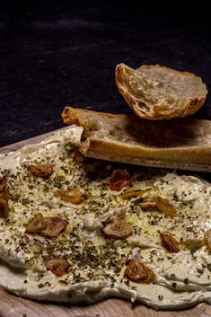 a pizza sitting on top of a cutting board covered in cheese and toppings next to a slice of bread