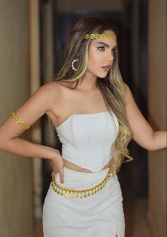 a woman with long blonde hair wearing a white dress and gold chain around her waist